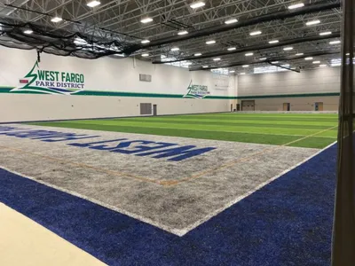 Indoor turf facility with West Fargo Park District logo on white wall