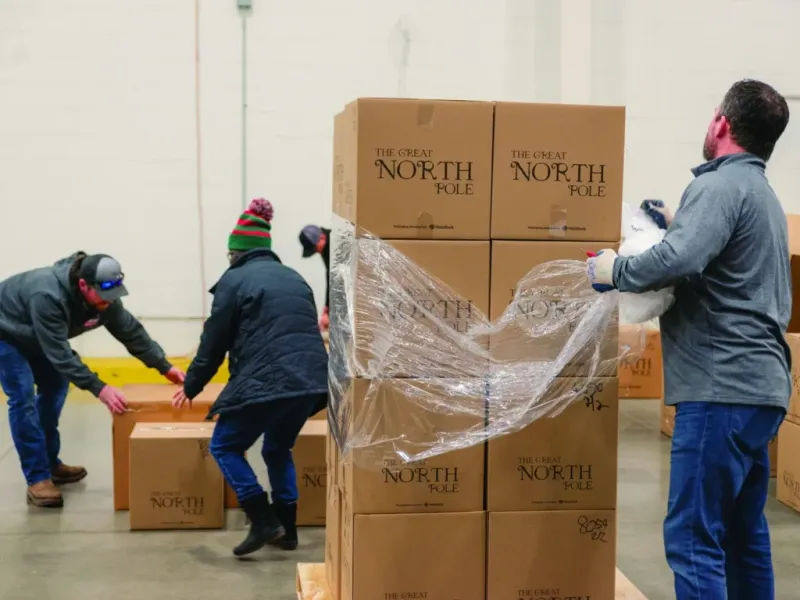 Volunteers unloading and wrapping pallets of 'The Great North Pole' donation boxes in a warehouse