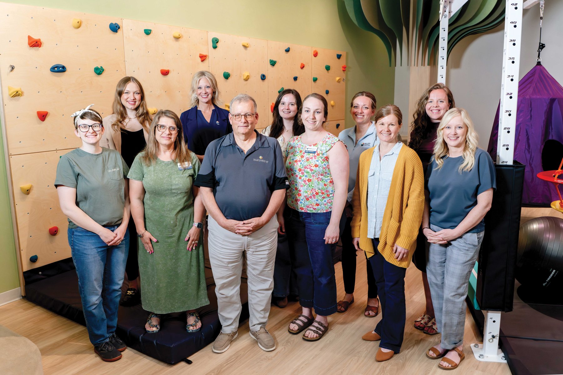 Valley Christian care team standing in front of the climbing wall at the Hulbert Children's Center in Fargo