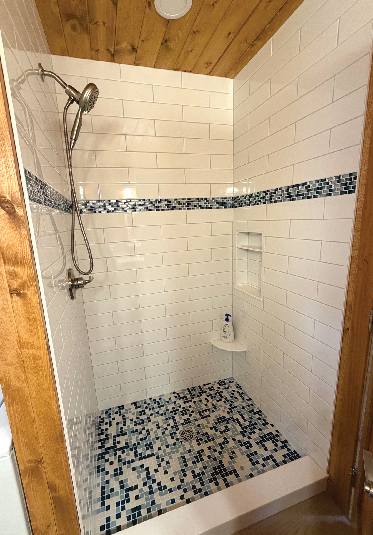 Primary shower with white tile and blue glass accent