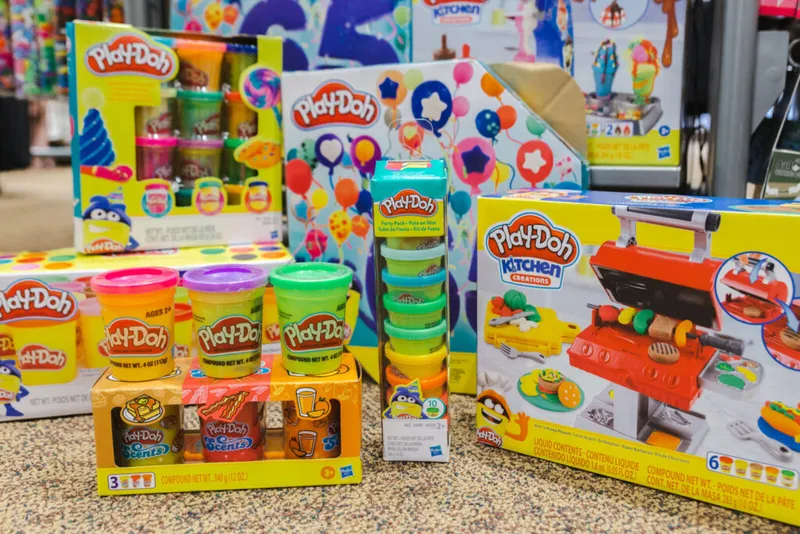 Assorted Play-Doh sets including Kitchen Creations grill and party packs displayed on a surface