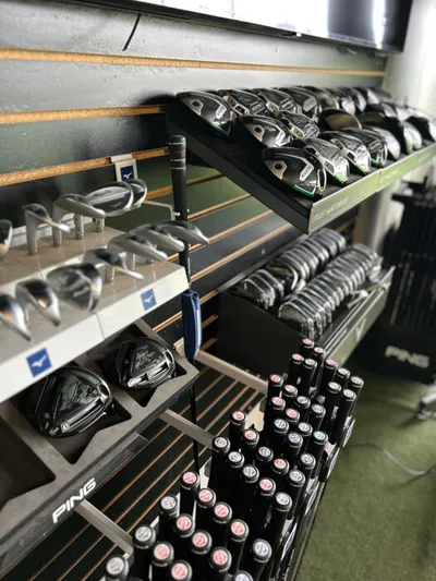 Golf club sets displayed on multi-tiered retail shelving, including Ping and Mizuno brands