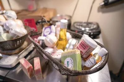 Wicker basket filled with handmade soaps, small bottled oils, and bath products on a counter