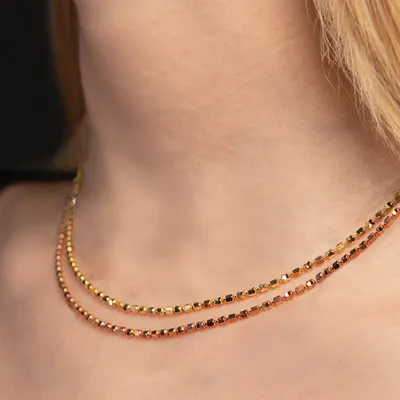 Two layered gold beaded necklaces worn close to the neck