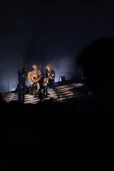 Two performers and a guitarist share a dimly lit stage amid smoky backlighting