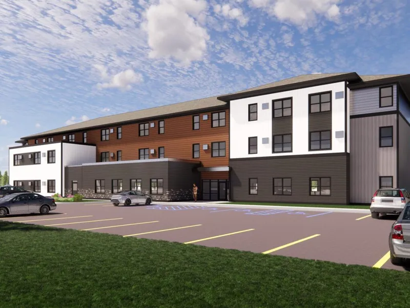Architectural rendering of a three-story residential facility with a parking lot in front