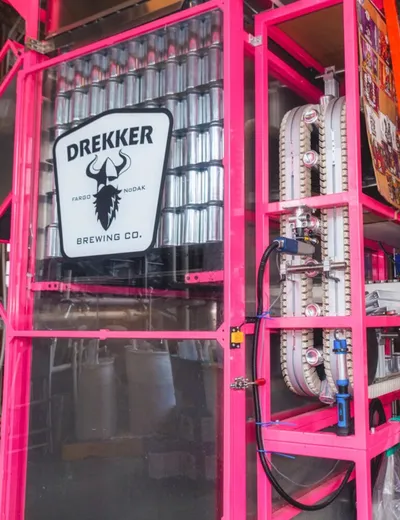 Drekker Brewing Co. sign on a bright pink shelving unit inside a brewery