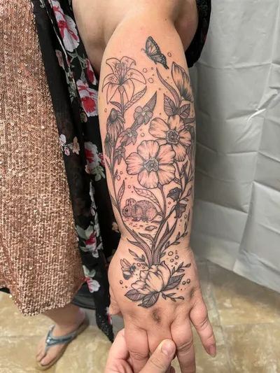 Black-and-grey floral and rabbit tattoo covering a forearm and hand