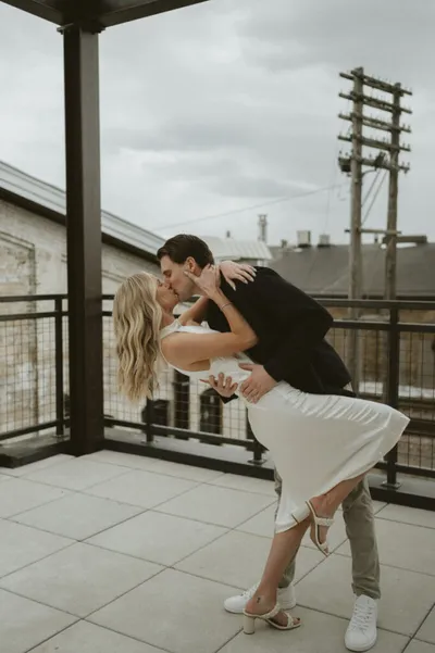 Couple sharing a romantic dip kiss on an urban rooftop terrace under overcast skies