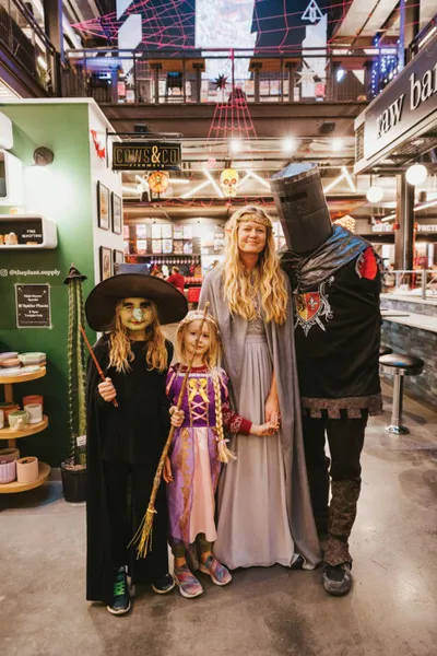 Family of four in Halloween costumes inside a decorated indoor market