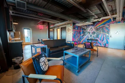 Industrial lounge with bold graffiti mural, black sofa, leather chairs, and a blue rolling coffee table