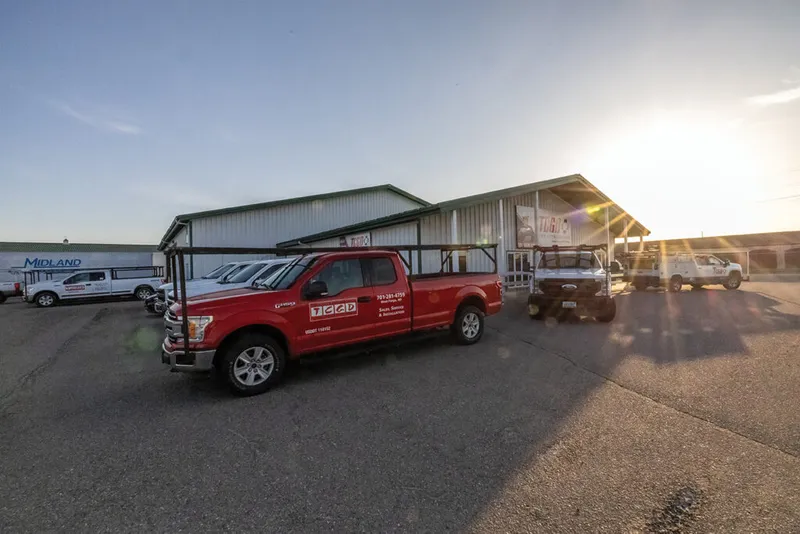 Red branded service truck parked outside a metal commercial building at sunset