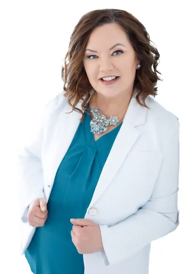 Smiling woman in white blazer and teal top with a jeweled statement necklace