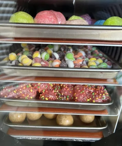 Four metal trays of colorful freeze-dried candies stacked on display shelves
