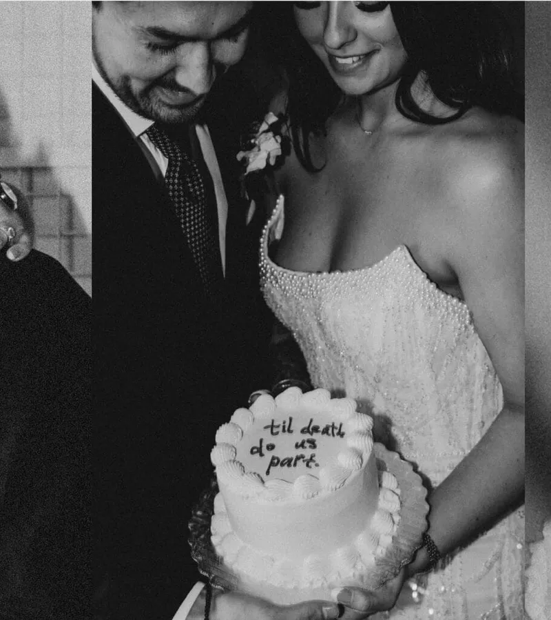 Bride and groom cutting a small cake reading 'til death do us part' in black and white