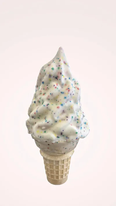 Soft-serve vanilla ice cream cone with colorful sprinkles on a waffle cone