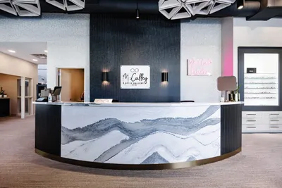 Curved marble-look reception desk in a modern optometry office with dark accent wall