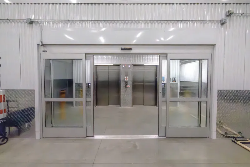 Open stainless steel elevator doors inside a modern climate-controlled storage facility