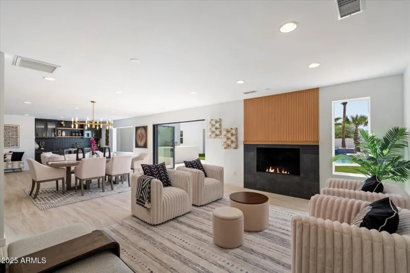 Open-plan living room with lit fireplace, ribbed armchairs, and dining area beyond