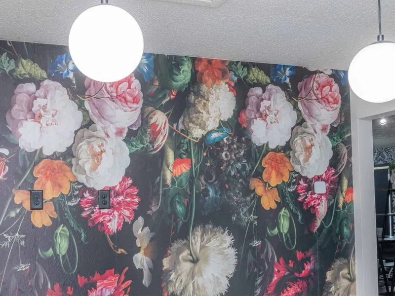 Bold dark floral wall mural with globe pendant lights in a bright interior space