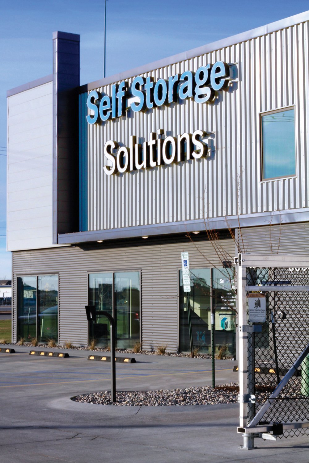 Exterior of a Self Storage Solutions building with its sign on a metal-sided facade