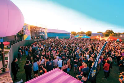 Large crowd gathered at an outdoor music festival stage at dusk