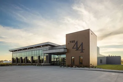 Modern brick event venue with large glass facade and "The 44" signage under a cloudy sky