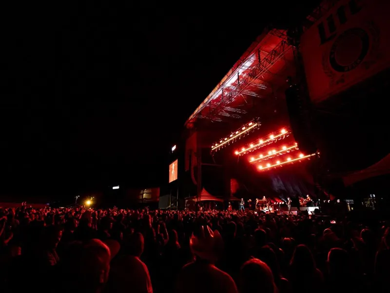 Large outdoor concert crowd bathed in red stage lighting at night