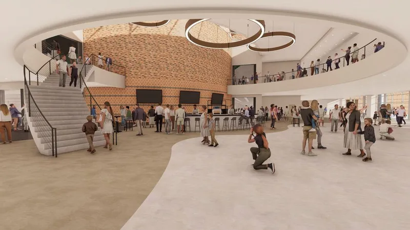 Architectural rendering of a spacious arena lobby with a curved staircase, circular ceiling feature, and crowds of people