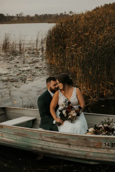 Bride and groom share a tender moment in a rustic rowboat among lakeside reeds
