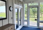 Sunlit entryway with white shiplap walls, glass French doors, and blue carpet flooring