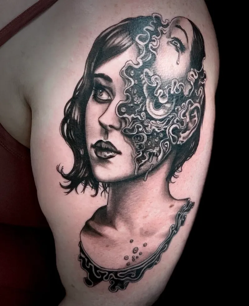 Black and grey upper arm tattoo of a woman's face dissolving into surreal swirling forms