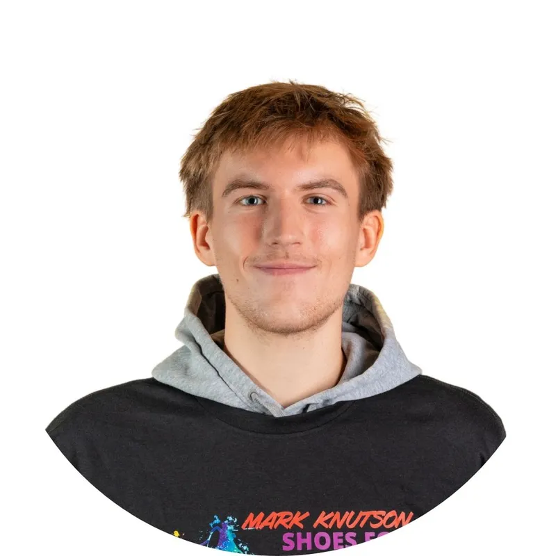 Young man with short auburn hair smiling, wearing a black graphic tee over a gray hoodie