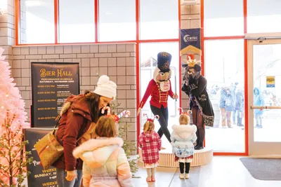 Children greeting costumed nutcracker characters at a festive indoor venue entrance