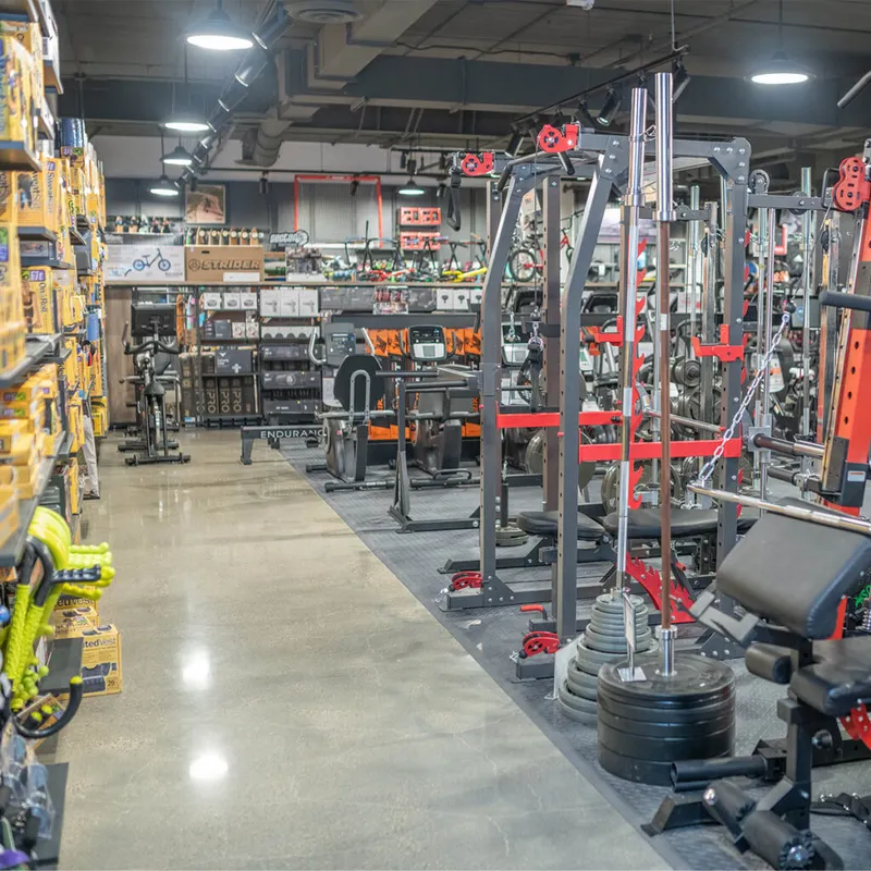 Sports store aisle with weight racks, cable machines, and shelves of boxed goods