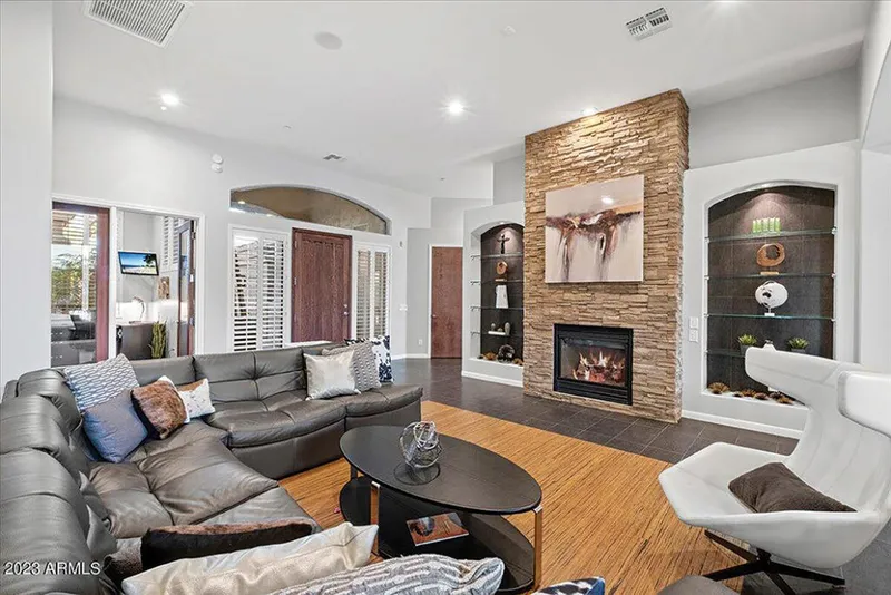 Modern living room with stacked-stone fireplace, gray sectional sofa, and built-in shelving