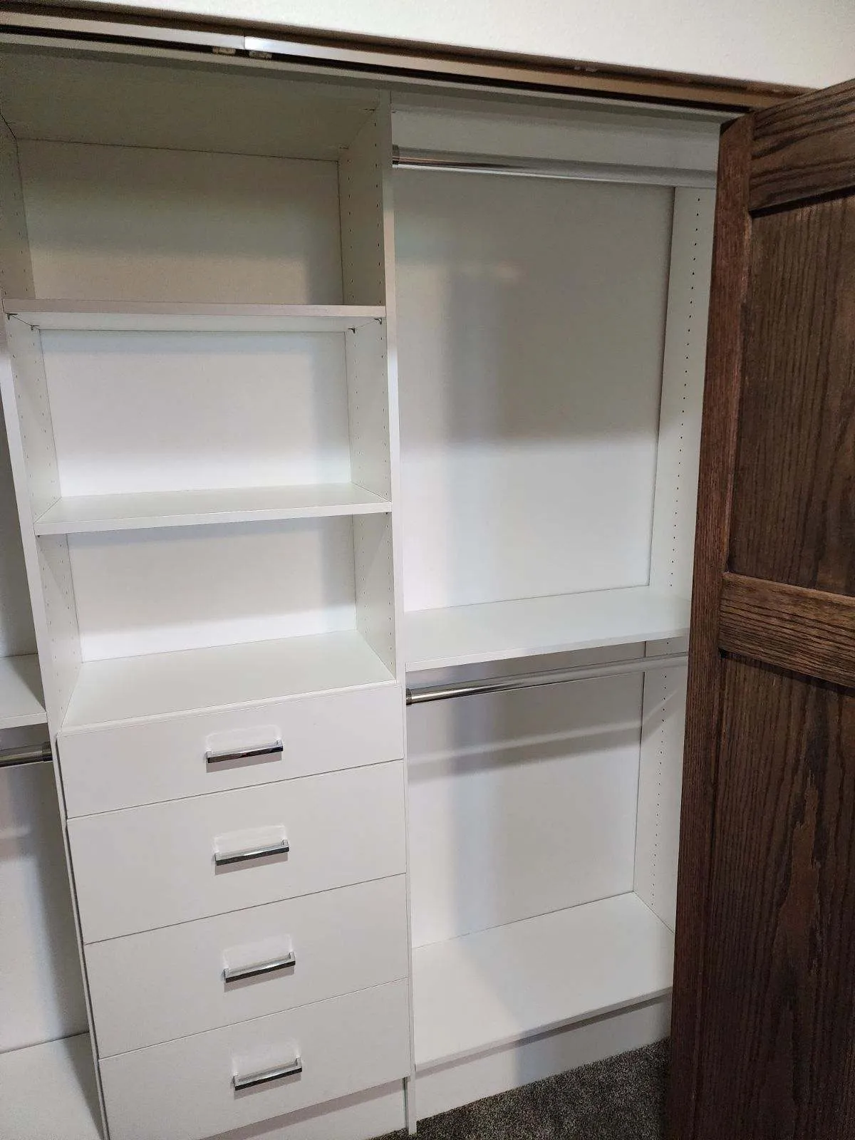 Empty white custom closet organizer with open shelves, four drawers, and two hanging rods