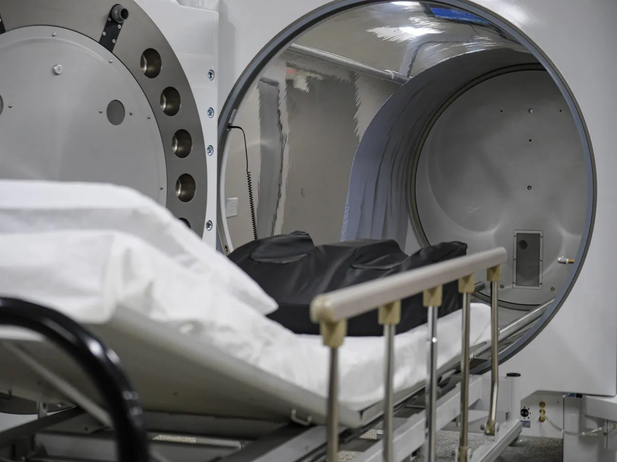 Hospital gurney partially inside an open hyperbaric chamber in a clinical room