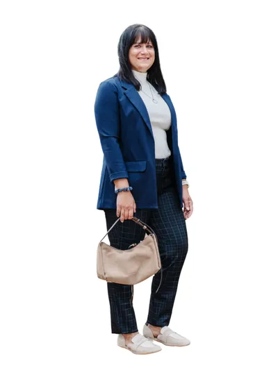 Woman in blue blazer, plaid trousers, and white flats holding a tan hobo bag
