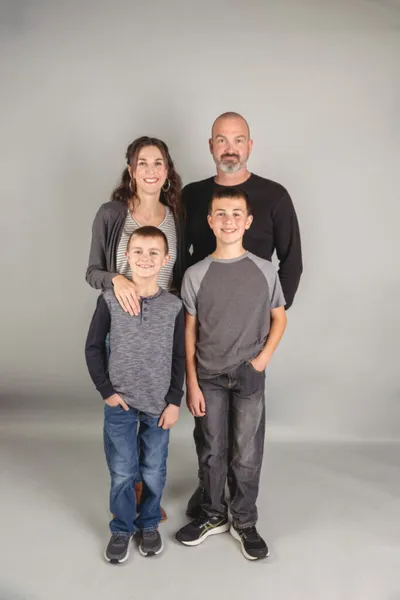 Family of four smiling together against a gray studio background