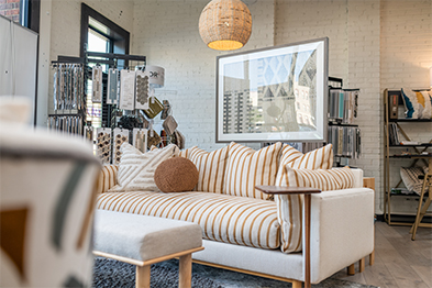 White and gold-striped sofa with matching pillows in a bright interior design studio