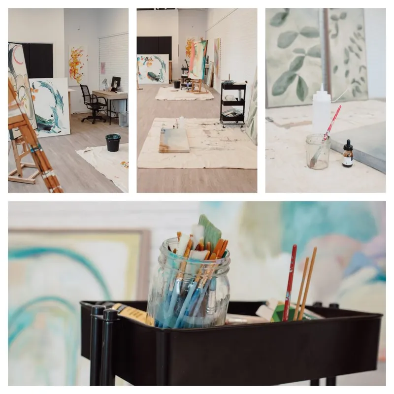 Bright art studio with easels, canvases, and a jar of paintbrushes on a black cart