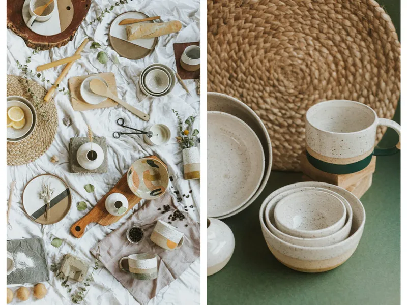 Handmade speckled ceramic bowls, mugs, and plates styled with wooden utensils and woven placemats