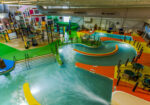 Indoor waterpark with colorful slides, lazy river, and splash zones viewed from above