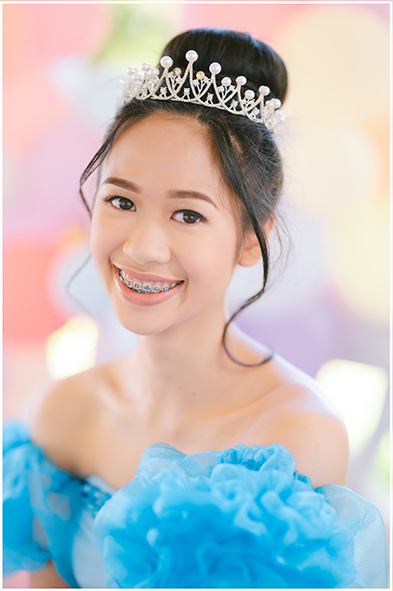 Smiling young woman in a blue ruffled gown and pearl tiara