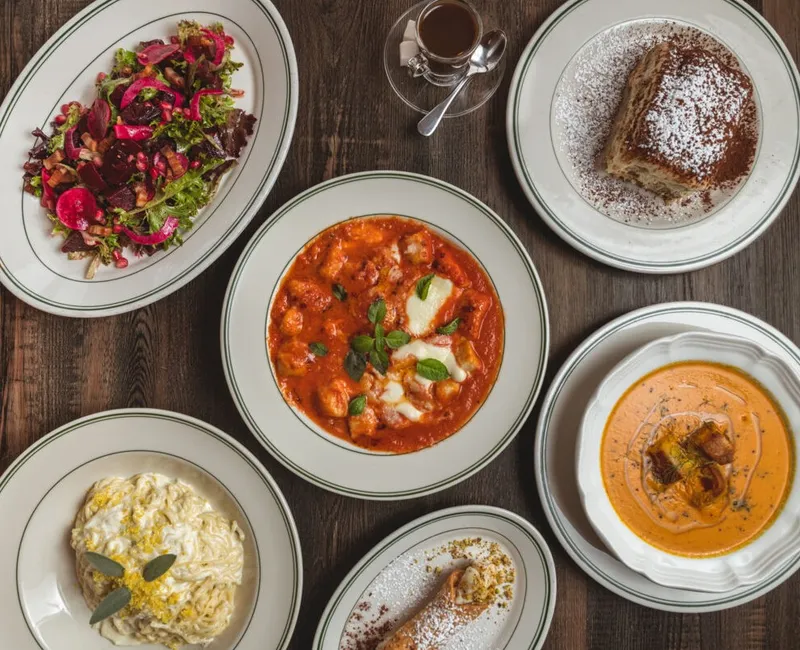 Overhead spread of six Italian-style dishes including tomato stew, creamy pasta, beet salad, soup, dessert, and espresso