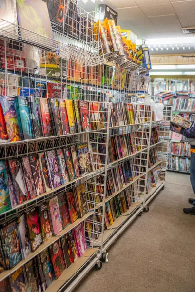 Crowded comic book store aisles with colorful comics filling wire display racks
