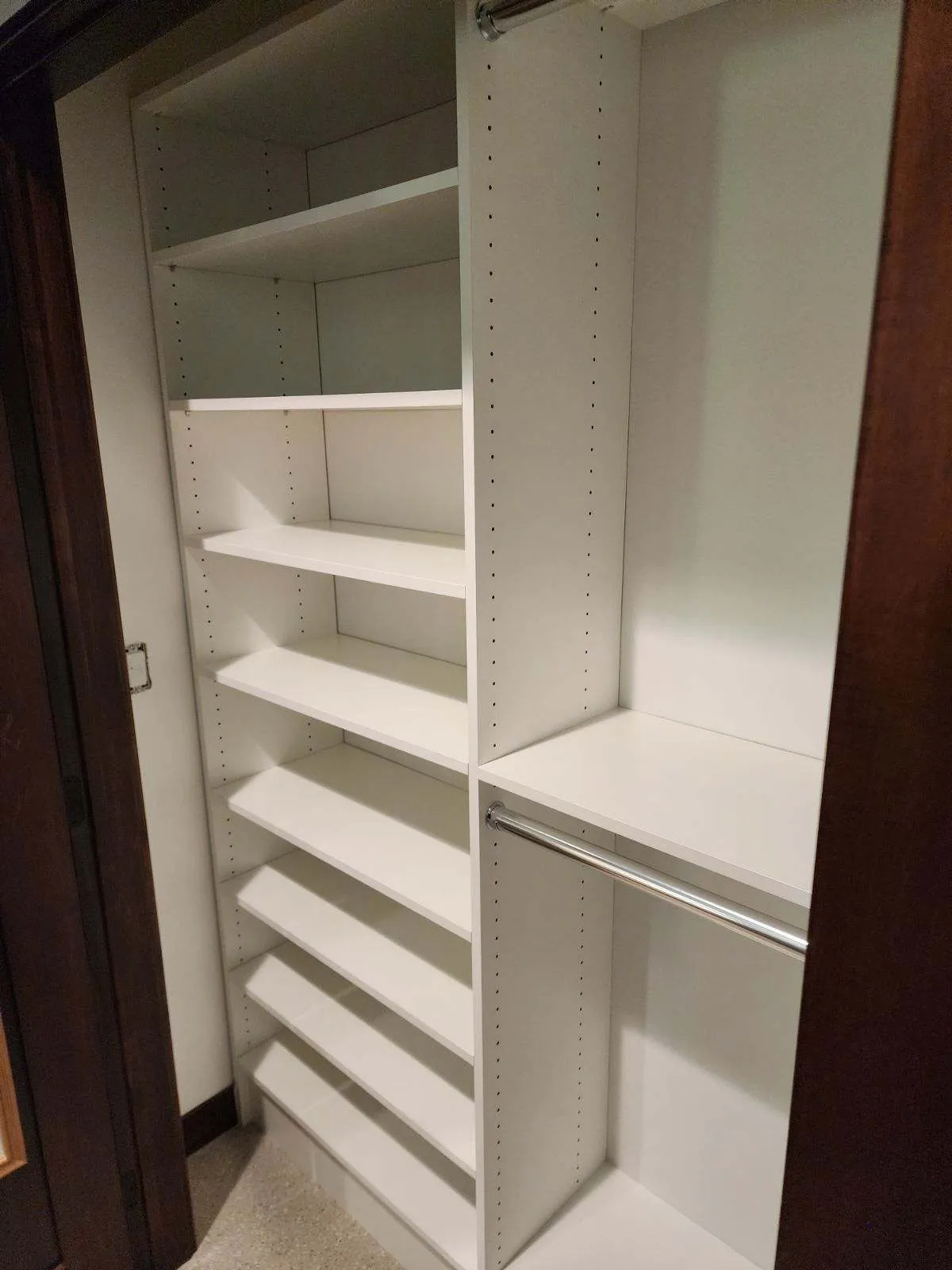 Empty custom closet with white adjustable shelving and chrome hanging rods