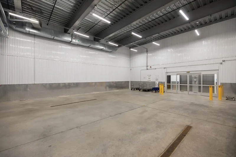 Spacious climate-controlled warehouse interior with concrete floors, white corrugated walls, and glass entry doors