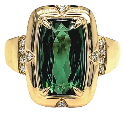 Gold cocktail ring featuring a large cushion-cut green stone accented by small diamonds